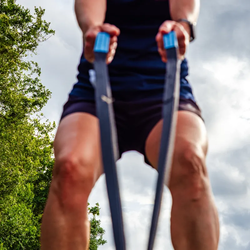 Persoon traint buiten met blauwe weerstandsbanden, passend bij de persoonlijke aanpak van Fitcoach Wilma op de contactpagina