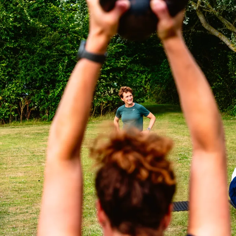 Buitentraining in het park: een deelnemer heft een kettlebell terwijl de trainer toekijkt, passend bij de persoonlijke aanpak van FitCoach Wilma
